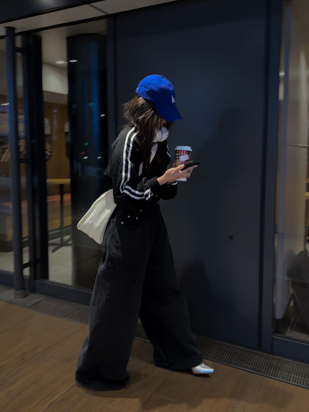 ブラック系のブルゾン、ブラック系のデニムパンツ、ホワイト系のショルダーバッグを着用したレディースの秋コーディネートの2枚目の写真