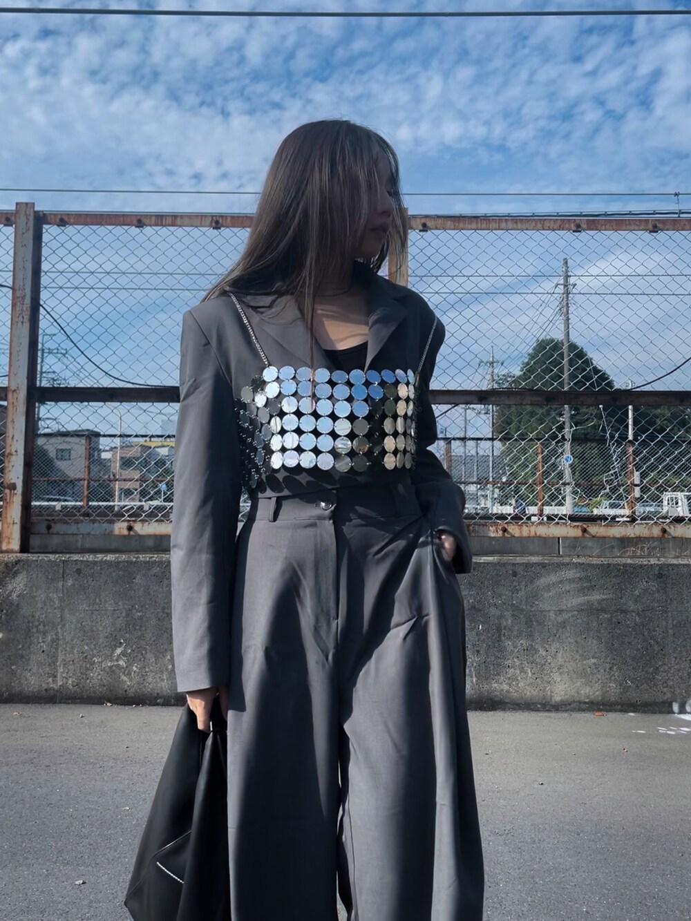 グレー系のセットアップ、ブラック系のハンドバッグ、シルバー系のファッション雑貨を着用したレディースの冬コーディネートの5枚目の写真