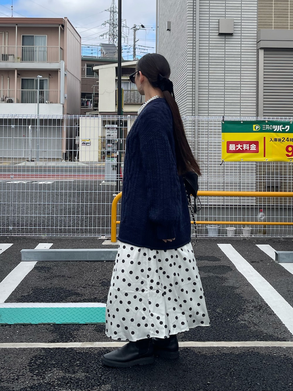 ホワイト系のスカート、ブラック系のバックパック/リュック、ブルー系のニット/セーターを着用したレディースの冬コーディネートの2枚目の写真