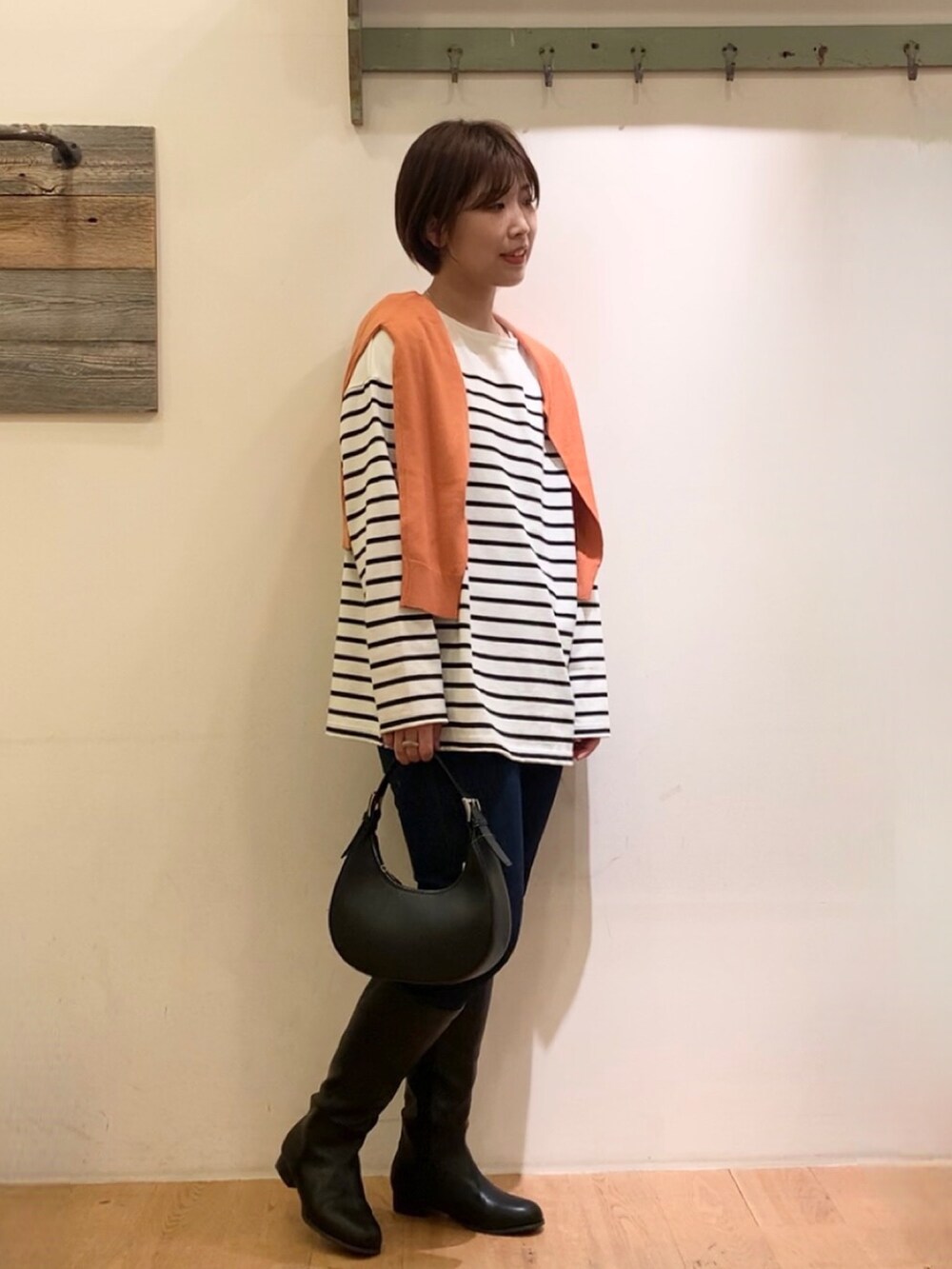 オレンジ系のカーディガン/ボレロ、ホワイト系のTシャツ/カットソー、ブルー系のデニムパンツを着用したレディースの秋コーディネートの2枚目の写真