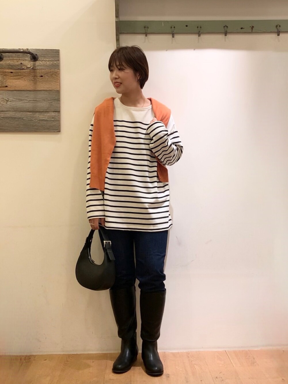 オレンジ系のカーディガン/ボレロ、ホワイト系のTシャツ/カットソー、ブルー系のデニムパンツを着用したレディースの秋コーディネートの3枚目の写真