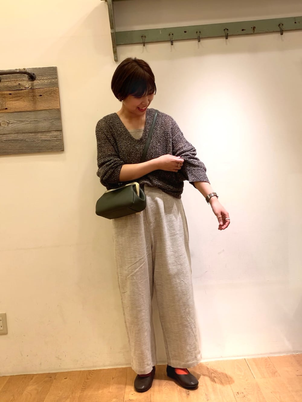 ブラック系のニット/セーター、ベージュ系のその他パンツ、グリーン系のハンドバッグを着用したレディースの夏コーディネートの2枚目の写真