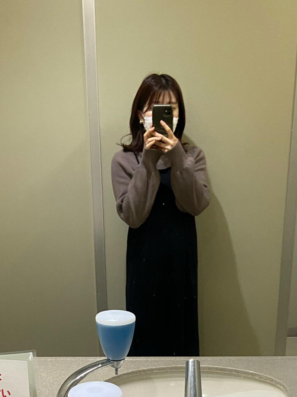 ブラック系のスニーカー、ベージュ系のステンカラーコート、ブラック系のワンピースを着用したレディースの秋コーディネートの2枚目の写真