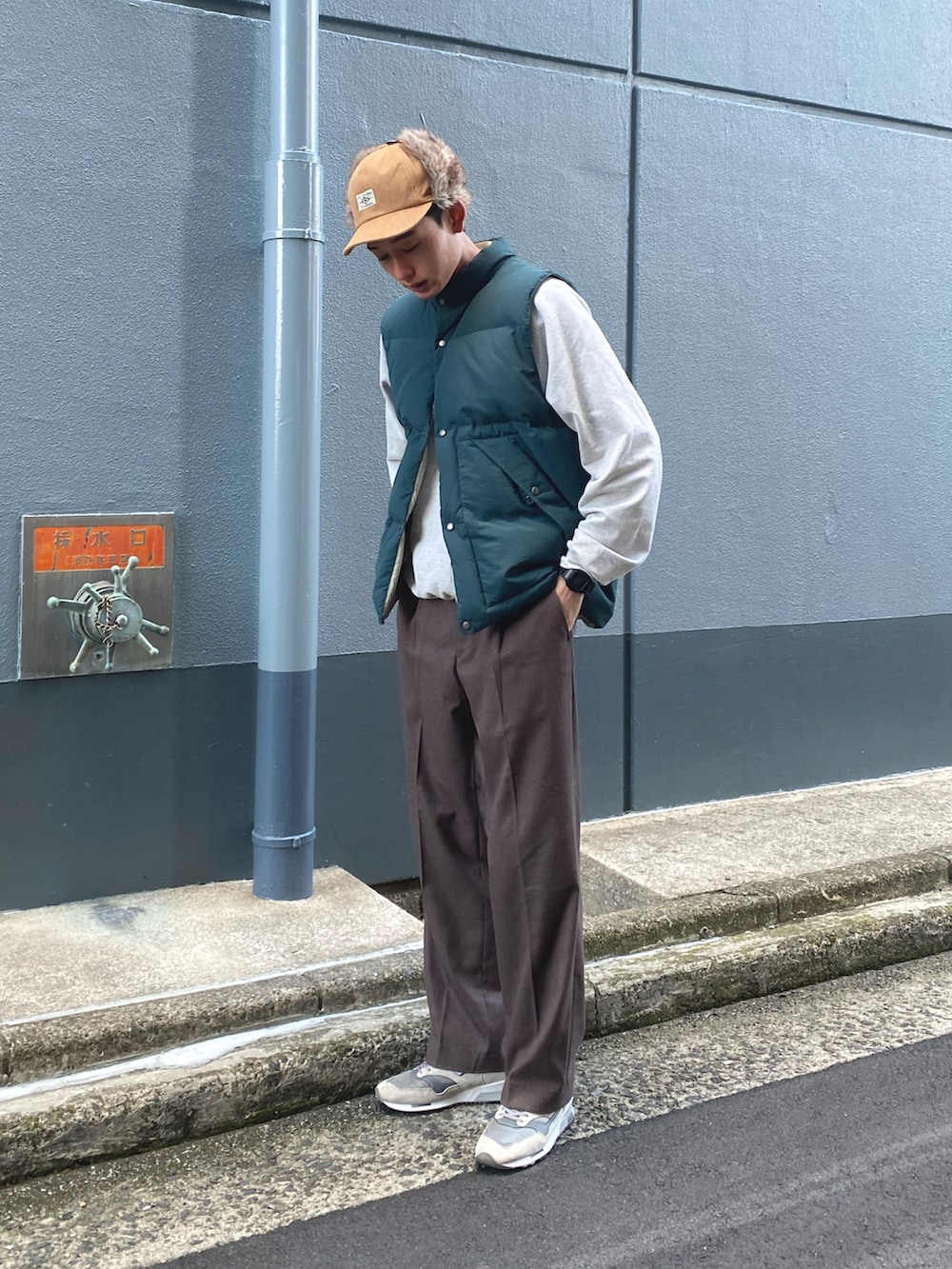 グリーン系のダウンベスト、グレー系のスニーカー、ベージュ系のキャップを着用したメンズの冬コーディネートの3枚目の写真