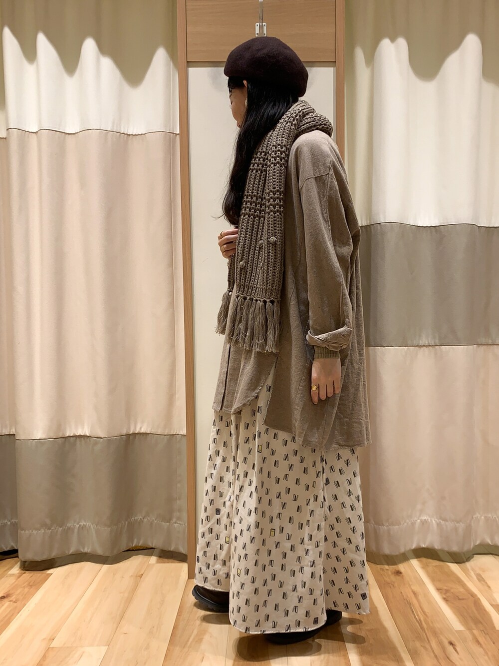 ブラウン系のチュニック、ブラウン系のニット/セーター、ホワイト系のスカートを着用したレディースの冬コーディネートの2枚目の写真