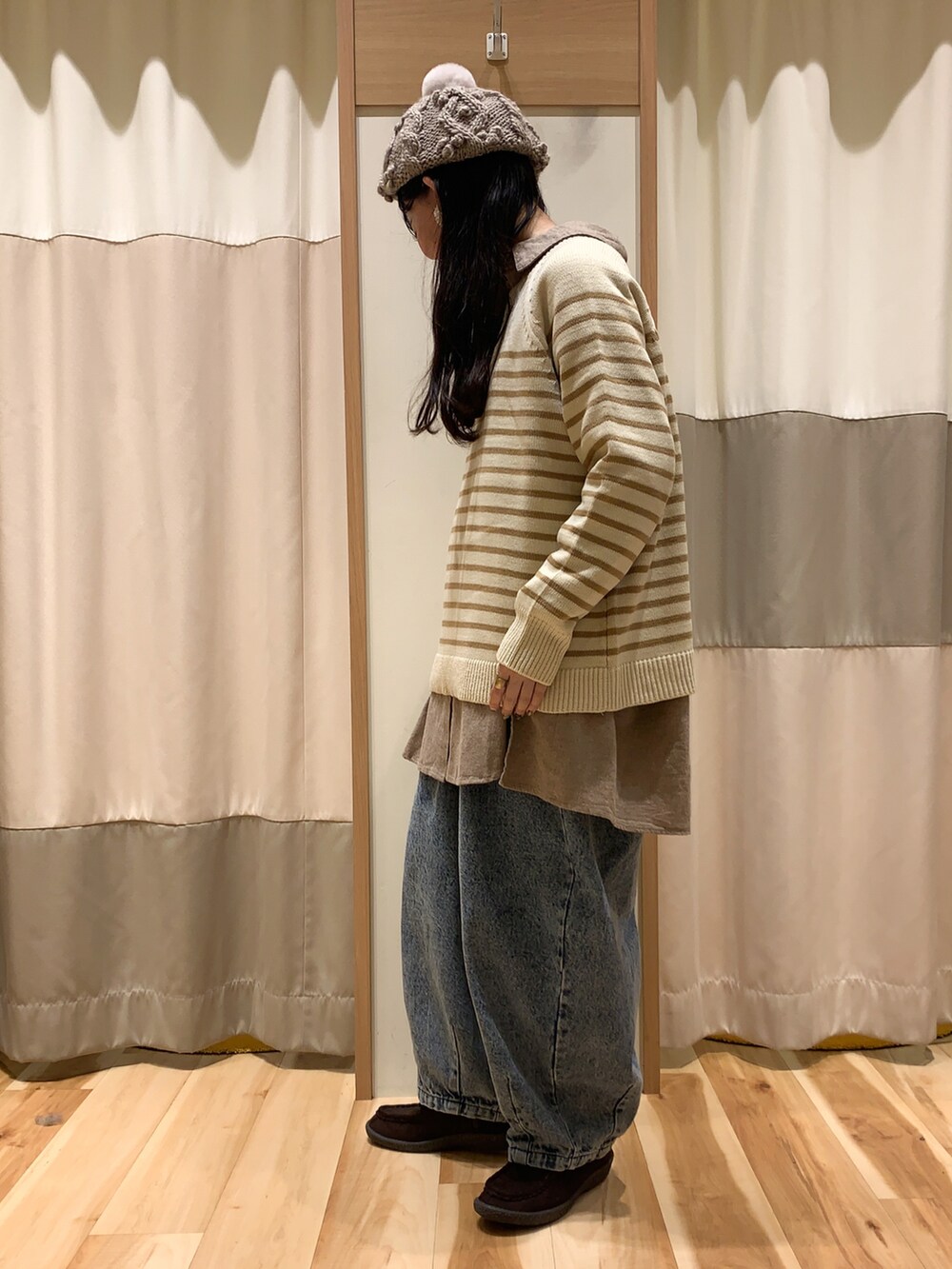 ベージュ系のニット/セーター、ブラウン系のチュニック、ブルー系のデニムパンツを着用したレディースの冬コーディネートの2枚目の写真