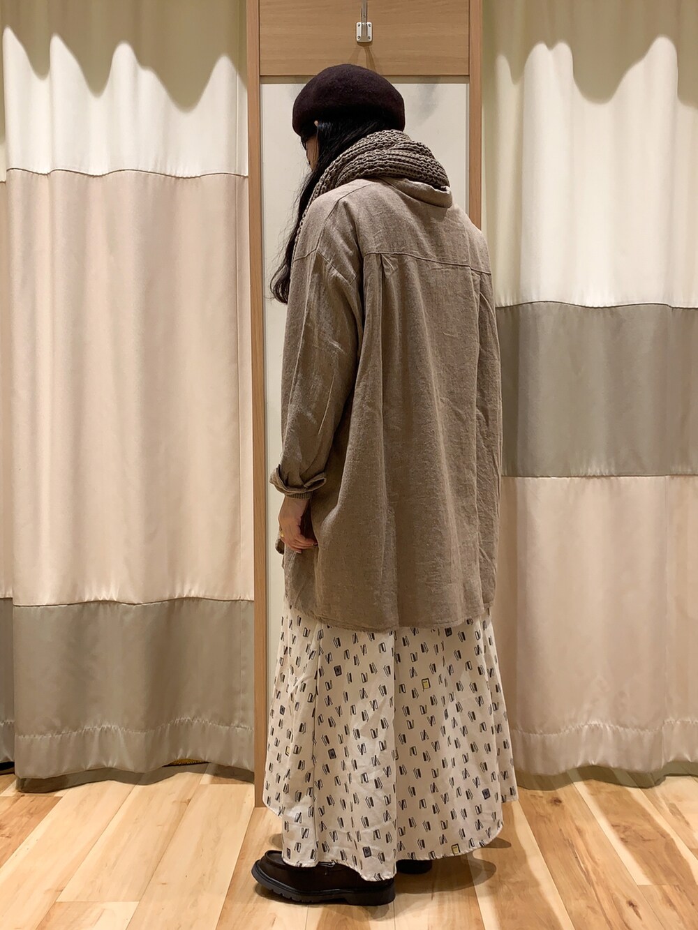 ブラウン系のチュニック、ブラウン系のニット/セーター、ホワイト系のスカートを着用したレディースの冬コーディネートの4枚目の写真