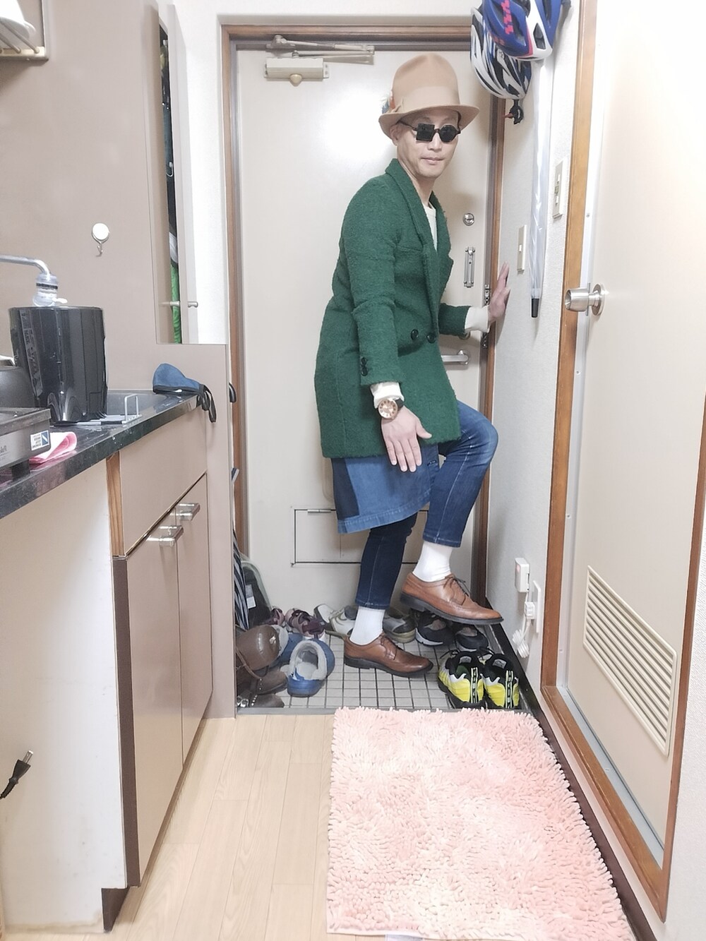 ブラウン系のローファー、グリーン系のチェスターコート、ブルー系のエプロンを着用したメンズの冬コーディネートの2枚目の写真