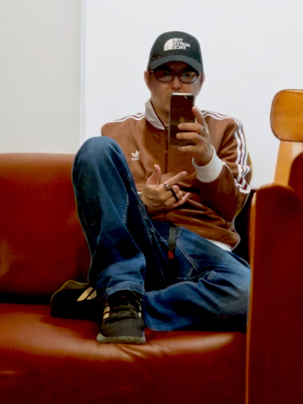 ブルー系のデニムパンツ、ブラウン系のジャージ、ブラック系のスニーカーを着用したメンズの冬コーディネートの2枚目の写真