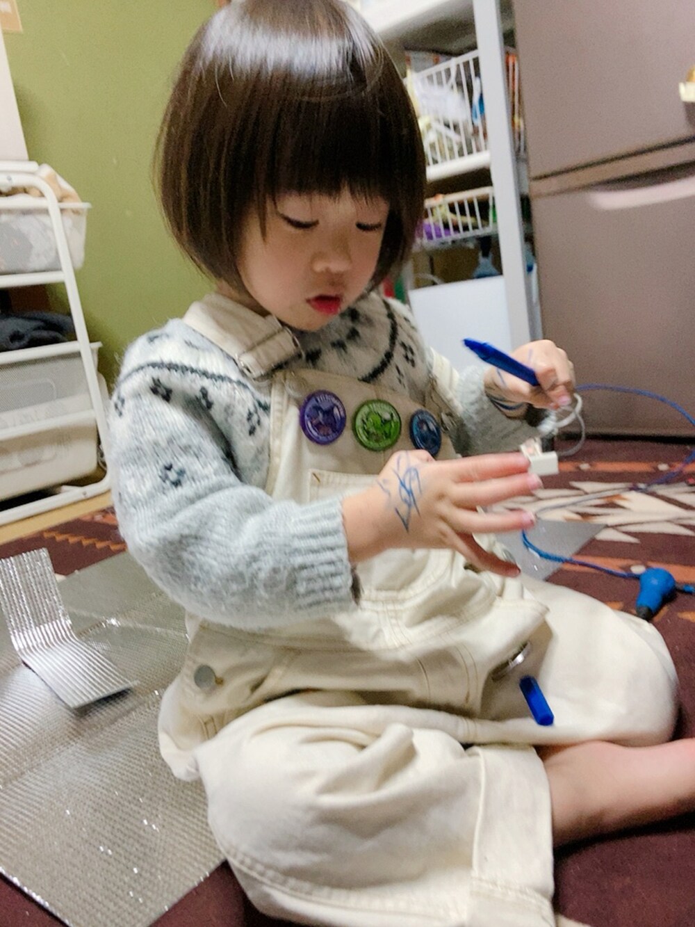 ホワイト系のサロペット/オーバーオール、グレー系のニット/セーターを着用したキッズの冬コーディネートの3枚目の写真