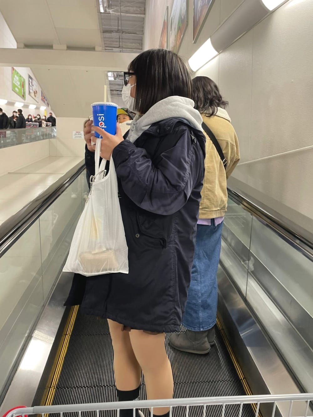 グレー系のパーカー、ブラウン系のスカート、ホワイト系のトートバッグを着用したレディースの冬コーディネートの2枚目の写真