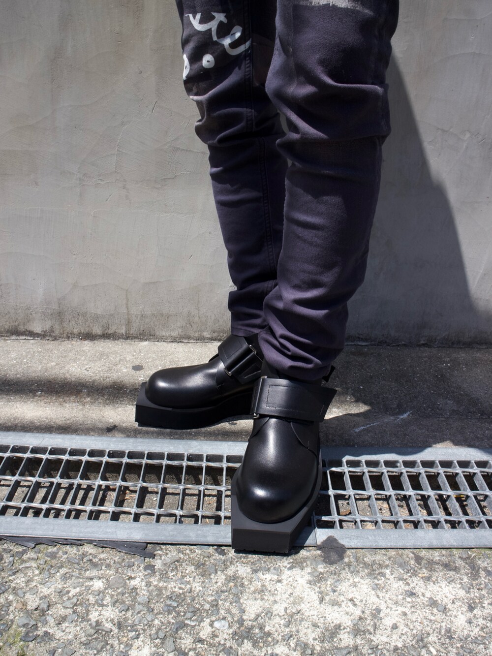 ブラック系のTシャツ/カットソー、ブラック系のデニムパンツ、ブラック系のブーツを着用したメンズの春コーディネートの5枚目の写真