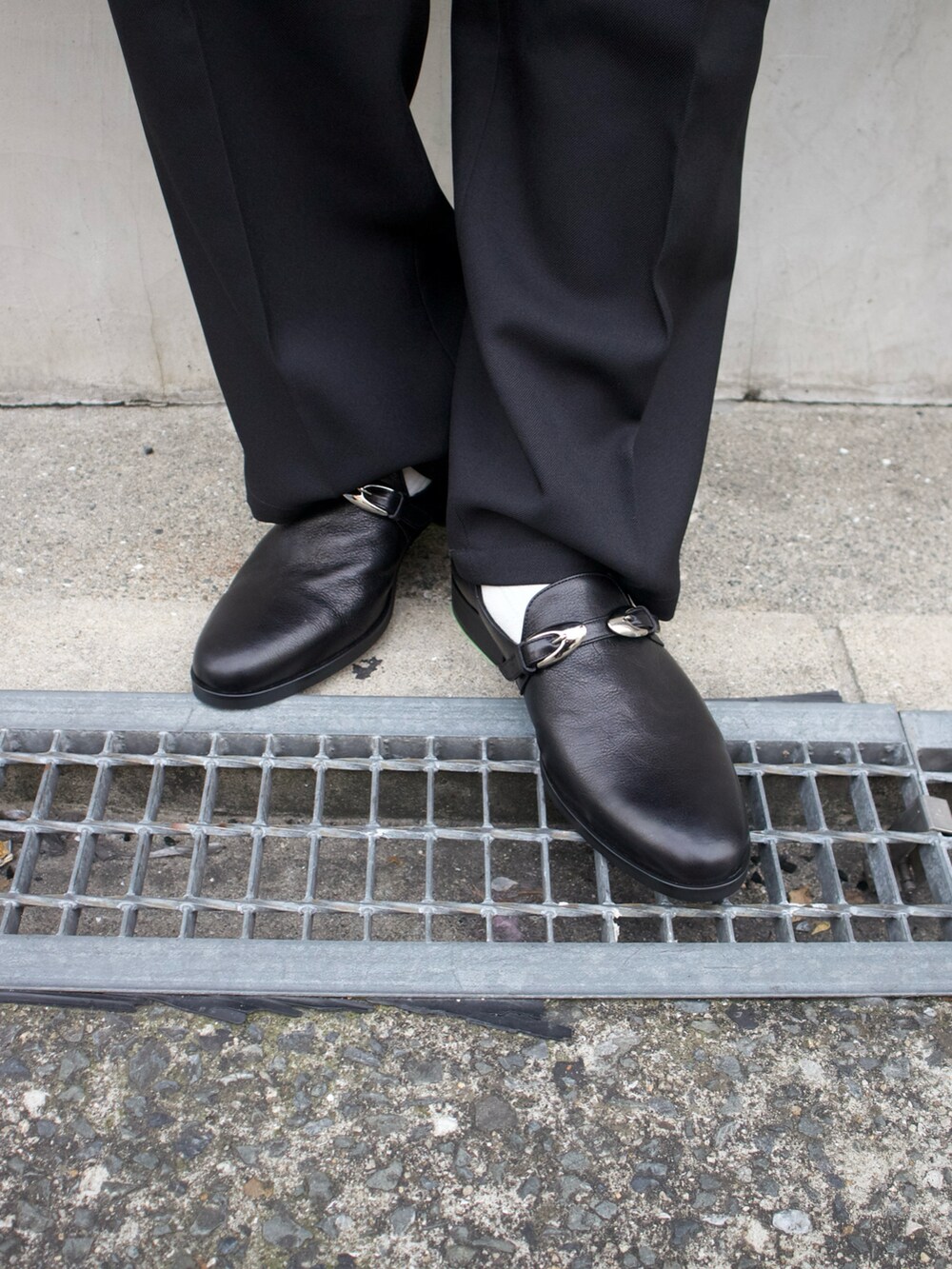 ブラック系のショルダーバッグ、ブラック系のスリッポン、グレー系のTシャツ/カットソーを着用したメンズの春コーディネートの2枚目の写真