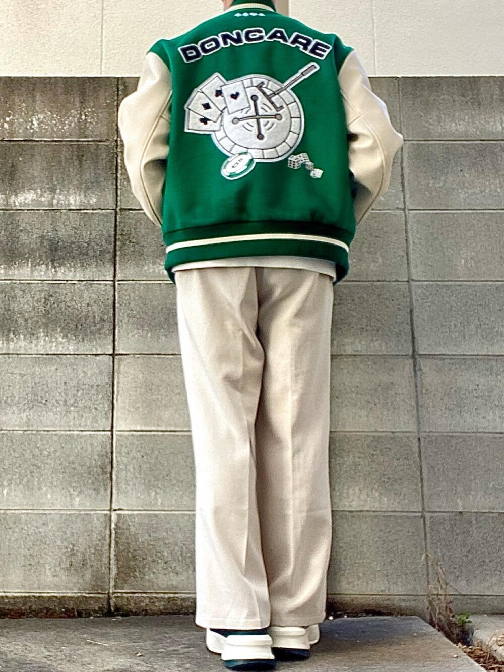 グリーン系のスタジャン、ホワイト系のスラックス、グリーン系のスニーカーを着用したメンズの冬コーディネートの2枚目の写真