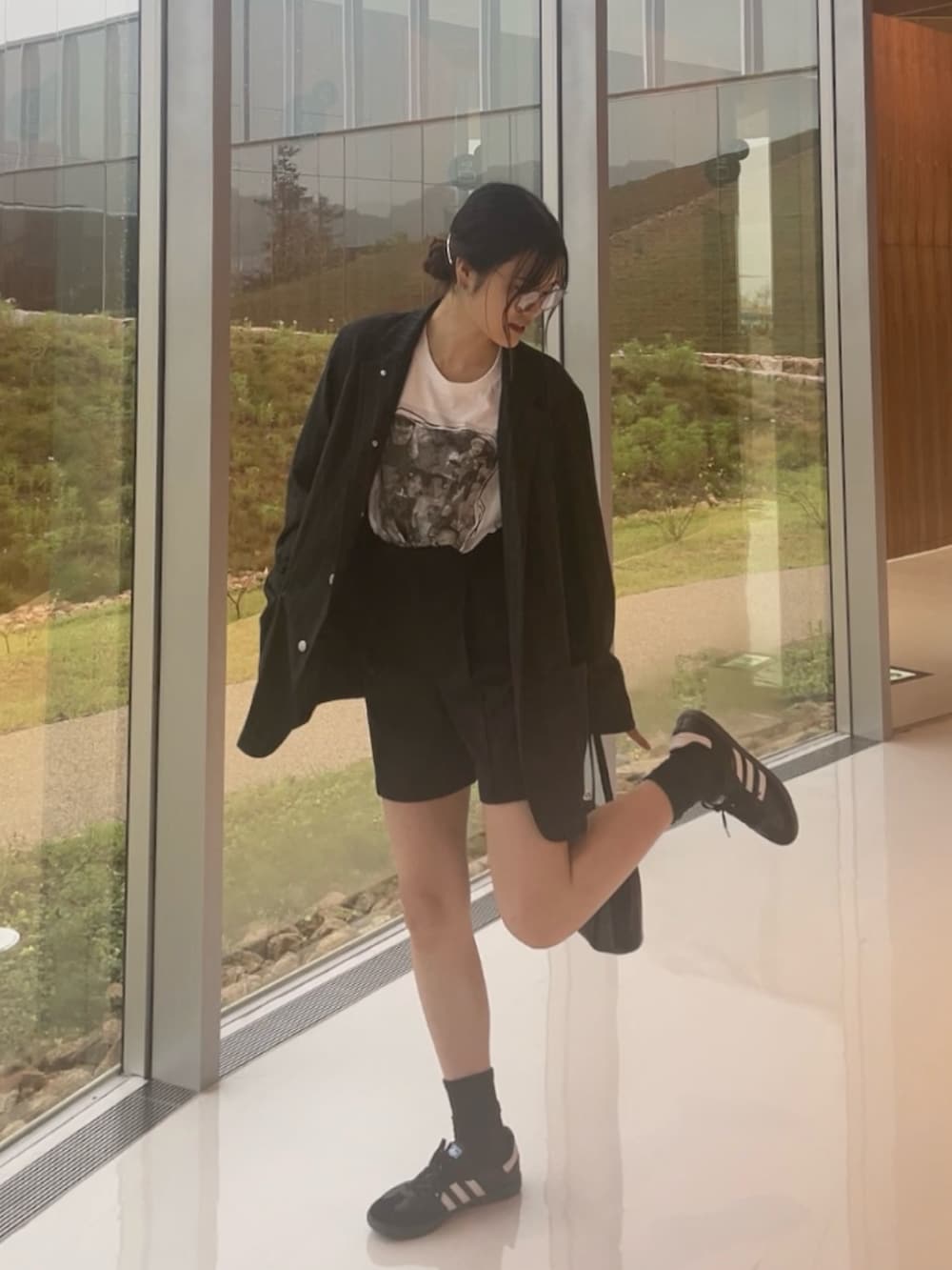 ホワイト系のスニーカー、ブラック系のハンドバッグを着用したレディースの秋コーディネートの2枚目の写真