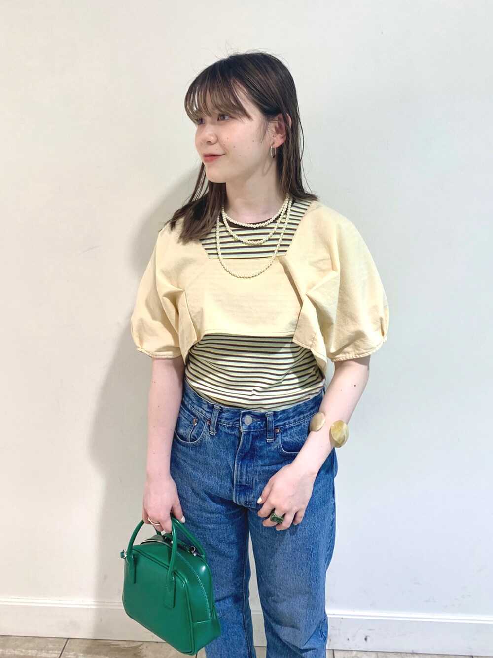 ベージュ系のシャツ/ブラウス、グリーン系のTシャツ/カットソー、ブルー系のデニムパンツを着用したレディースの夏コーディネートの2枚目の写真