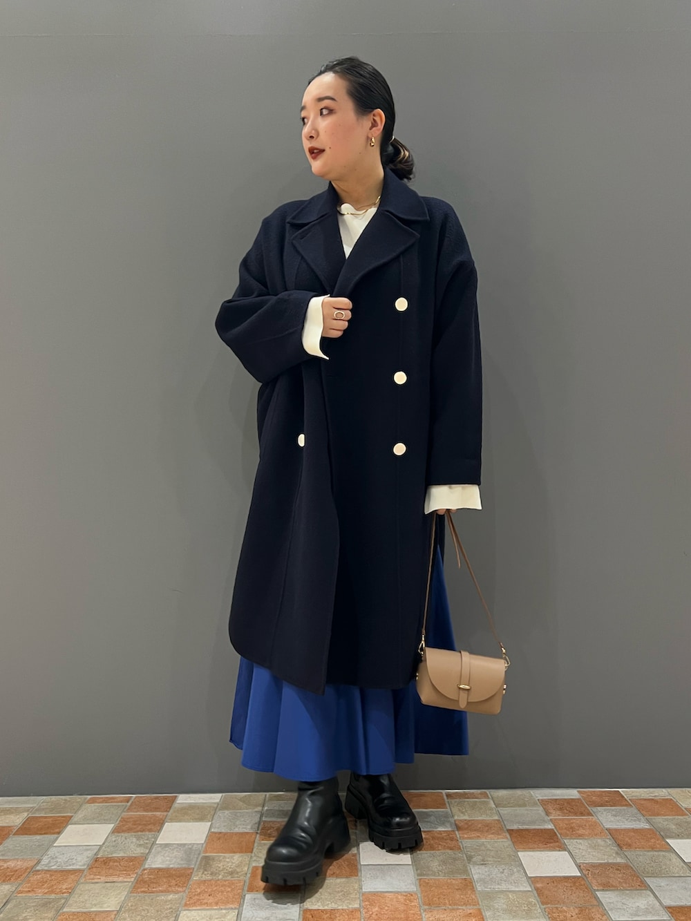 ブルー系のピーコート、ホワイト系のニット/セーター、ベージュ系のショルダーバッグを着用したレディースの秋コーディネートの3枚目の写真