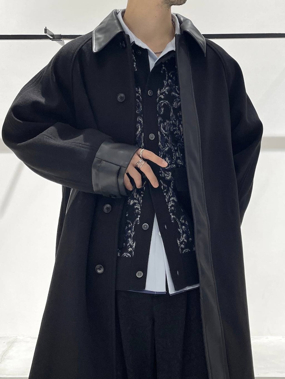 ブラック系のステンカラーコート、ブラック系のバレエシューズ、ブルー系のシャツ/ブラウスを着用したメンズの冬コーディネートの3枚目の写真