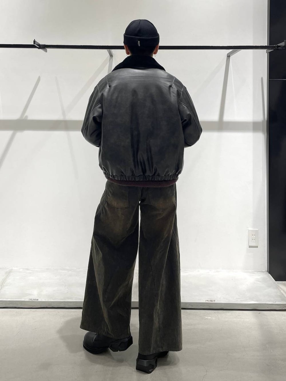 グレー系のブルゾン、レッド系のニット/セーター、ブラック系のドレスシューズを着用したメンズの秋コーディネートの2枚目の写真