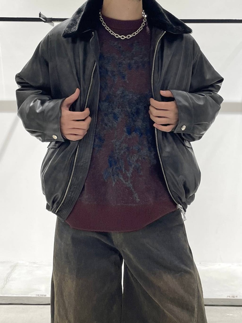 グレー系のブルゾン、レッド系のニット/セーター、ブラック系のドレスシューズを着用したメンズの秋コーディネートの3枚目の写真