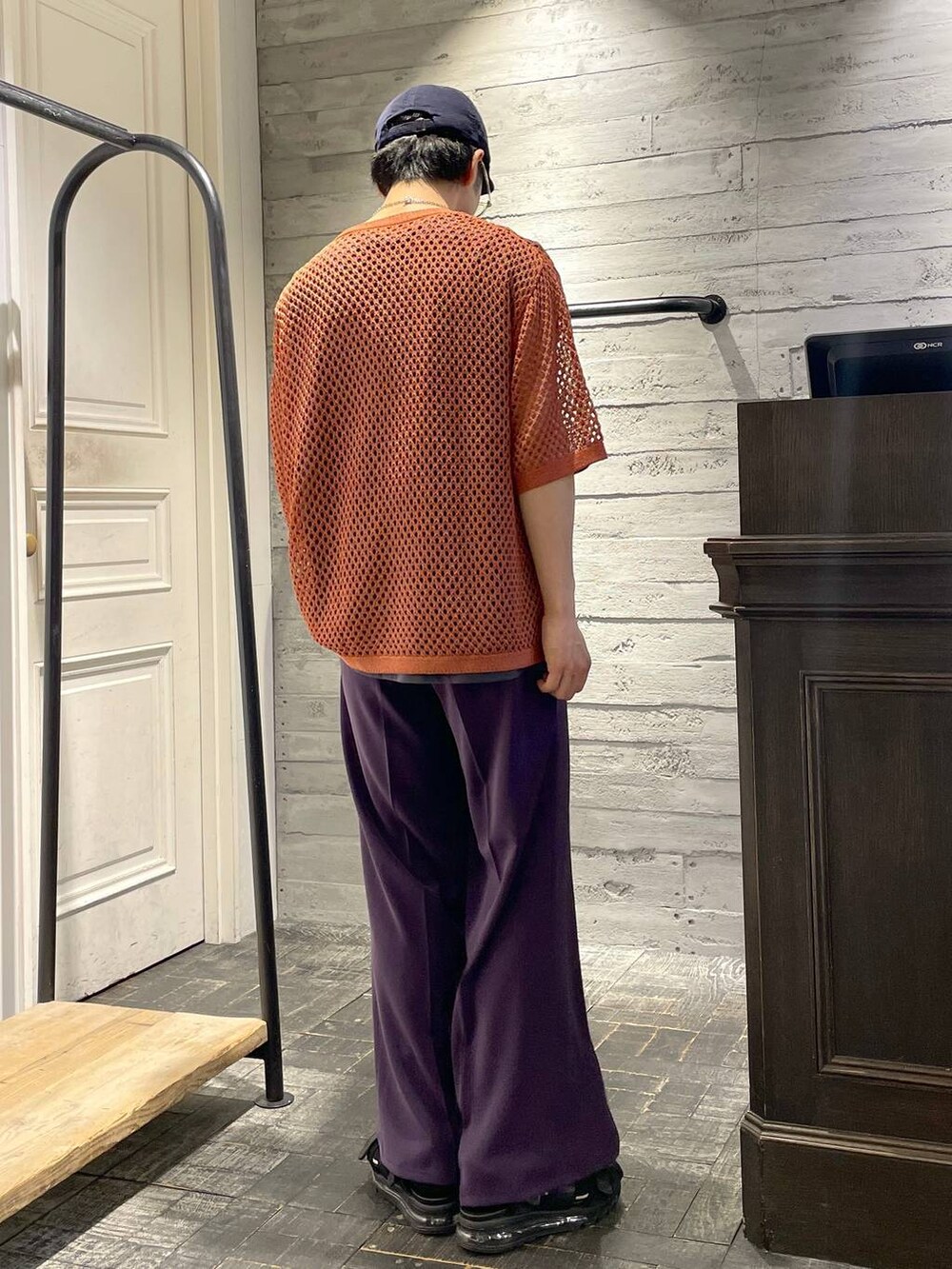 パープル系のスラックス、オレンジ系のニット/セーター、ブラック系のサンダルを着用したメンズの春コーディネートの2枚目の写真