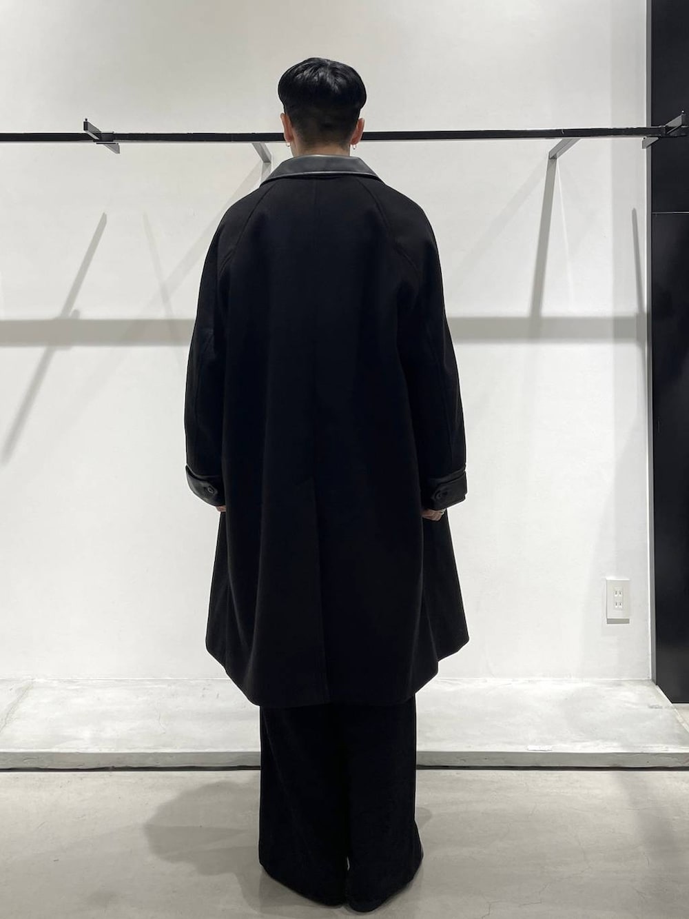 ブラック系のステンカラーコート、ブラック系のバレエシューズ、ブルー系のシャツ/ブラウスを着用したメンズの冬コーディネートの2枚目の写真