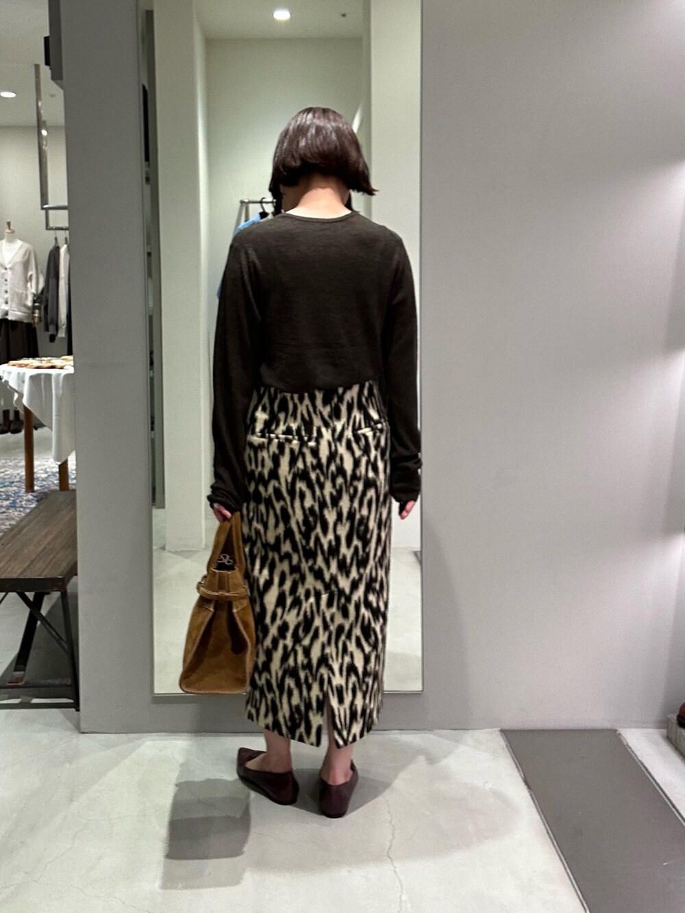 ブラウン系のスカート、グリーン系のニット/セーター、ブラウン系のトートバッグを着用したレディースの秋コーディネートの2枚目の写真