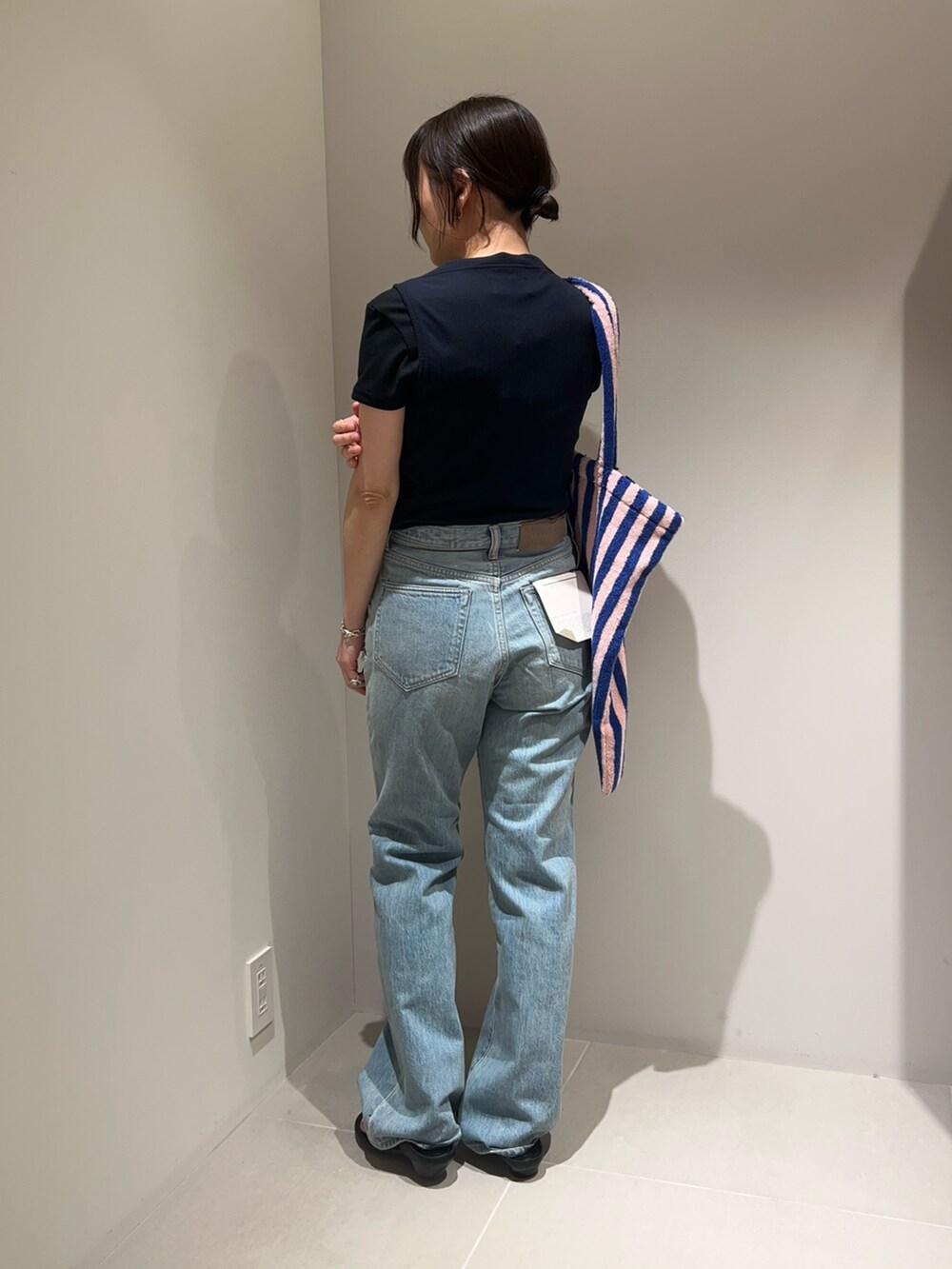 ブルー系のデニムパンツ、ブルー系のタンクトップ、ブルー系のトートバッグを着用したレディースの春コーディネートの2枚目の写真