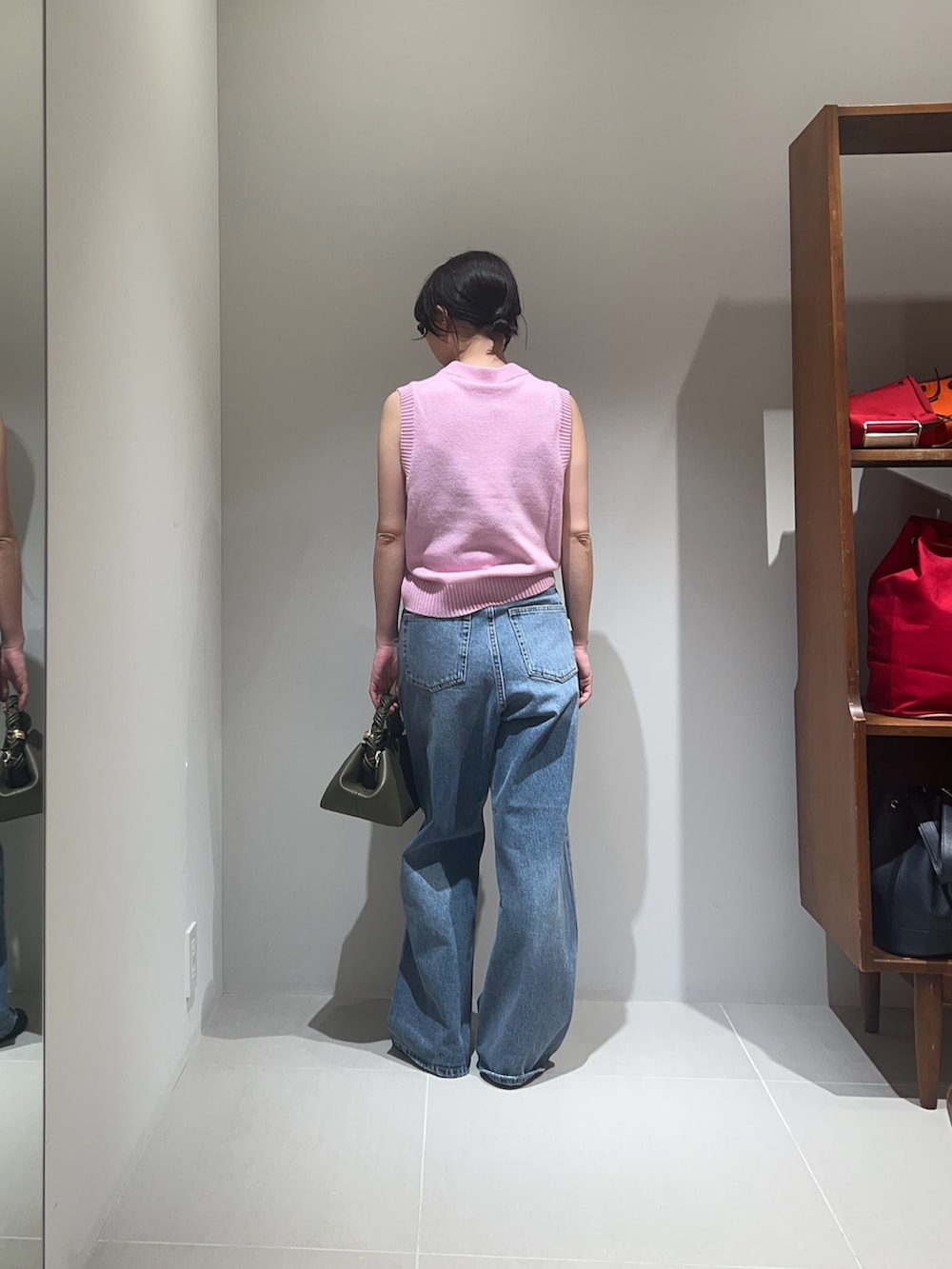 ピンク系のベスト、グリーン系のショルダーバッグ、ブルー系のデニムパンツを着用したレディースの秋コーディネートの2枚目の写真