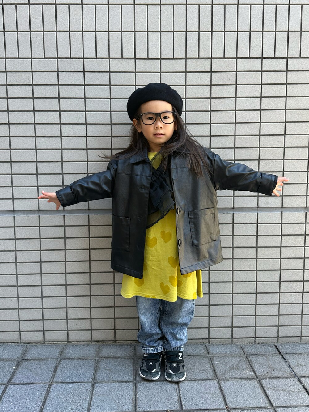 イエロー系のワンピース、ブルー系のデニムパンツ、ブラック系のスニーカーを着用したキッズの冬コーディネートの2枚目の写真