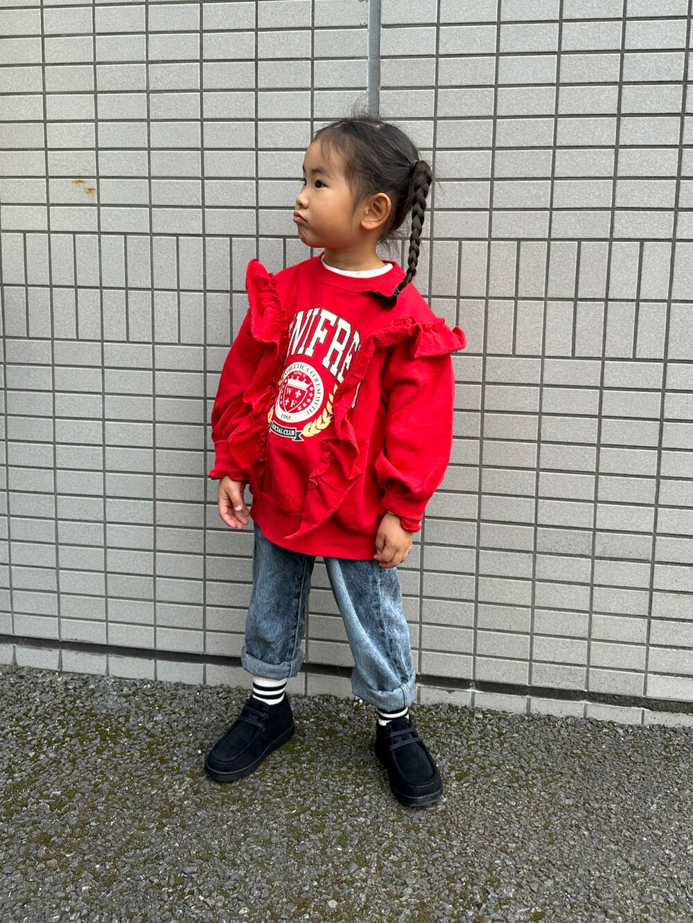 レッド系のスウェット、ブルー系のデニムパンツ、ブラック系のブーツを着用したキッズの冬コーディネートの2枚目の写真