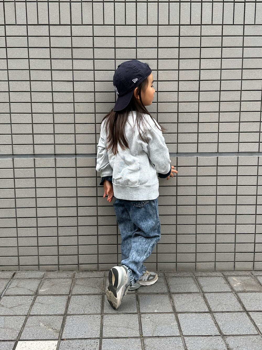 グレー系のスウェット、グレー系のスニーカー、ブルー系のデニムパンツを着用したキッズの冬コーディネートの2枚目の写真