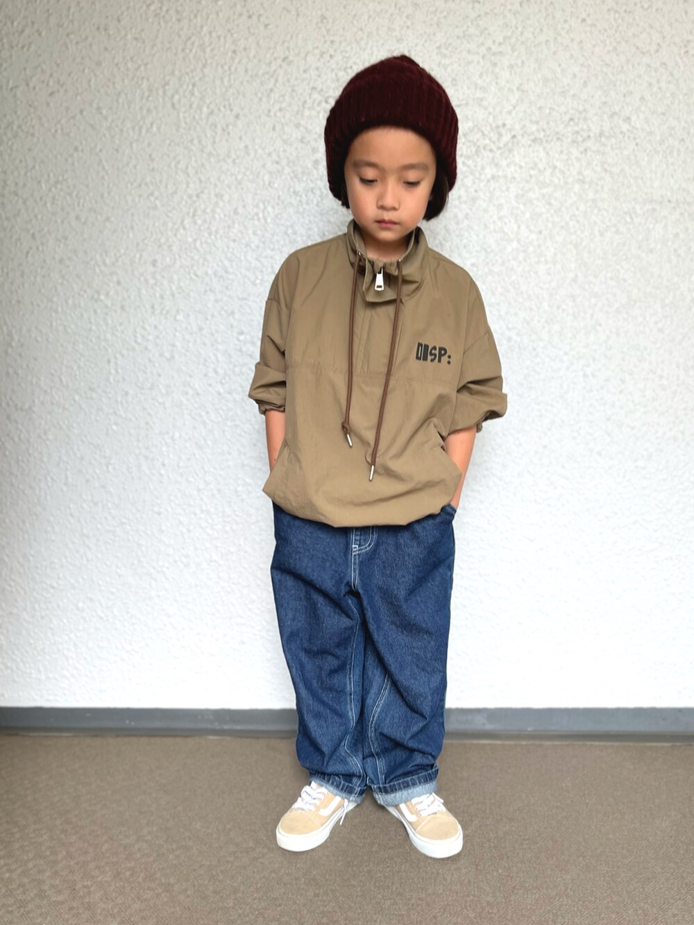 ブルー系のデニムパンツ、ベージュ系のスニーカー、ブラウン系のナイロンジャケットを着用したキッズの秋コーディネートの2枚目の写真