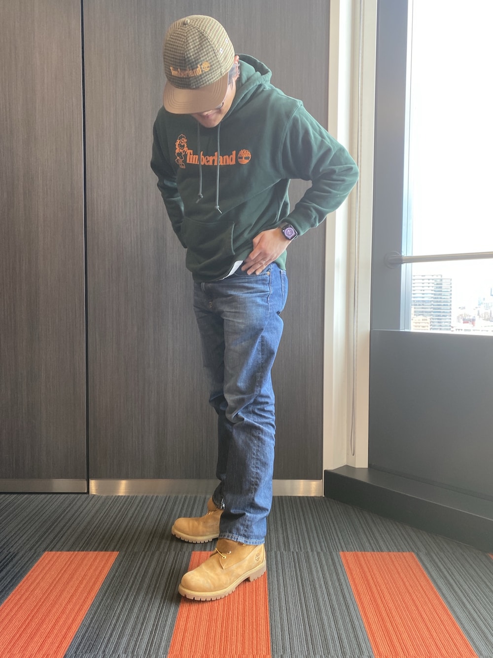 ベージュ系のブーツ、グリーン系のパーカー、ブラウン系のキャップを着用したメンズの冬コーディネートの2枚目の写真