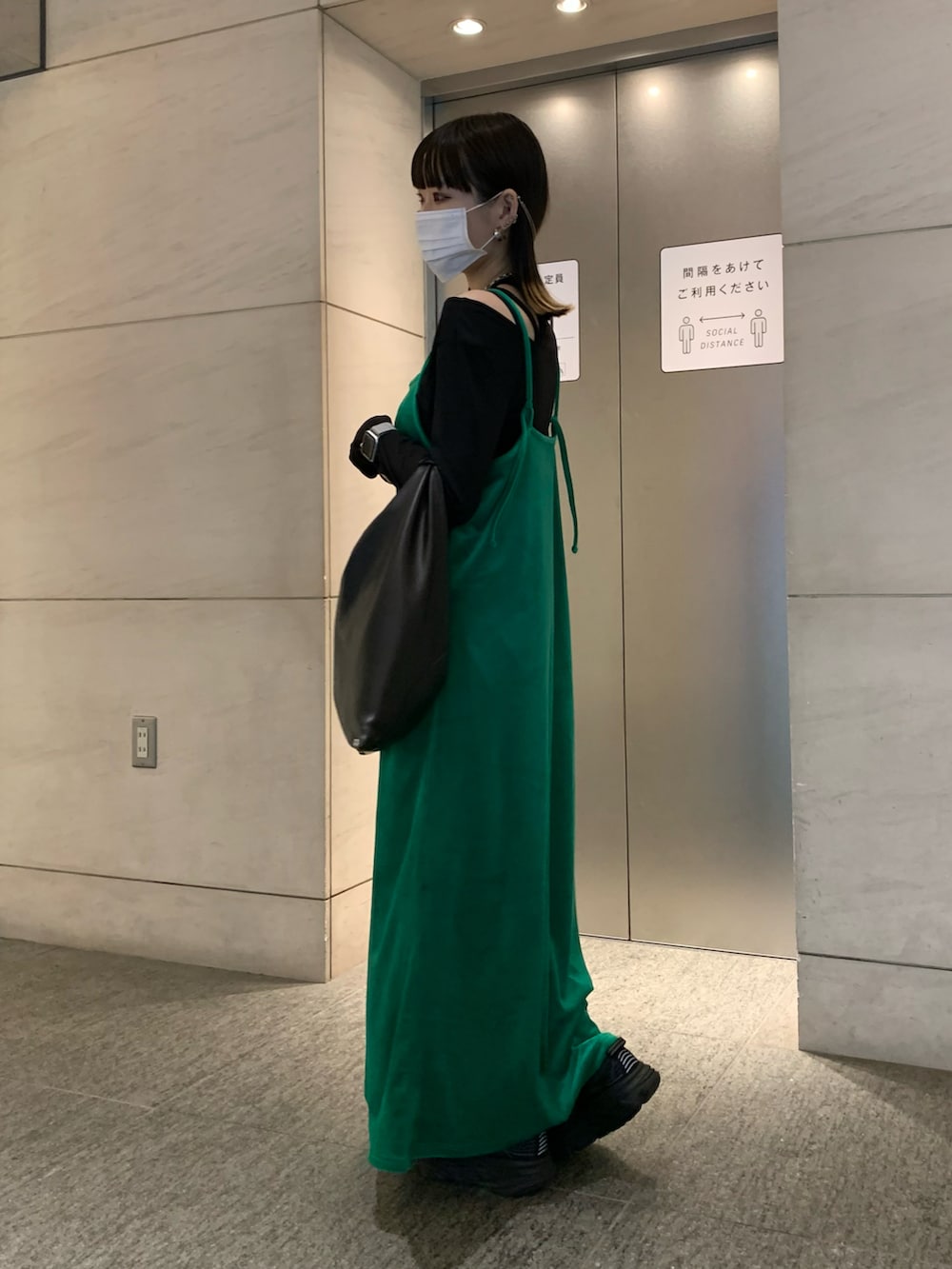 ブラック系のハンドバッグ、グリーン系のワンピース/ドレス、ブラック系のトップスを着用したレディースの秋コーディネートの2枚目の写真