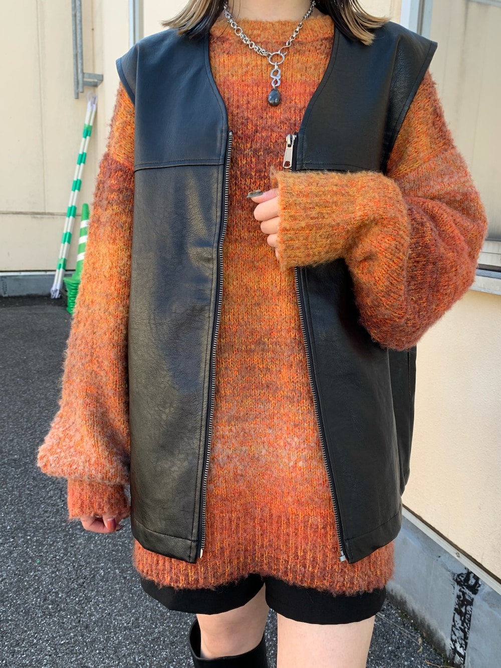 オレンジ系のニット/セーター、ブラック系のショルダーバッグ、ブラック系のブーツを着用したレディースの秋コーディネートの3枚目の写真