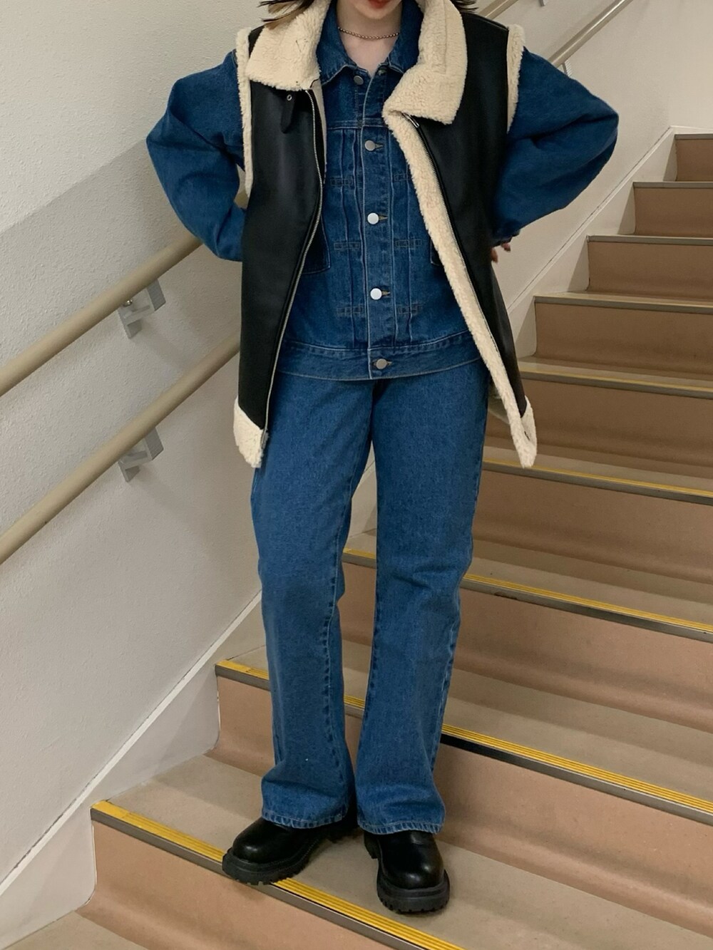 ブルー系のデニムパンツ、ブラック系のブーツ、ブラック系のベストを着用したレディースの秋コーディネートの2枚目の写真