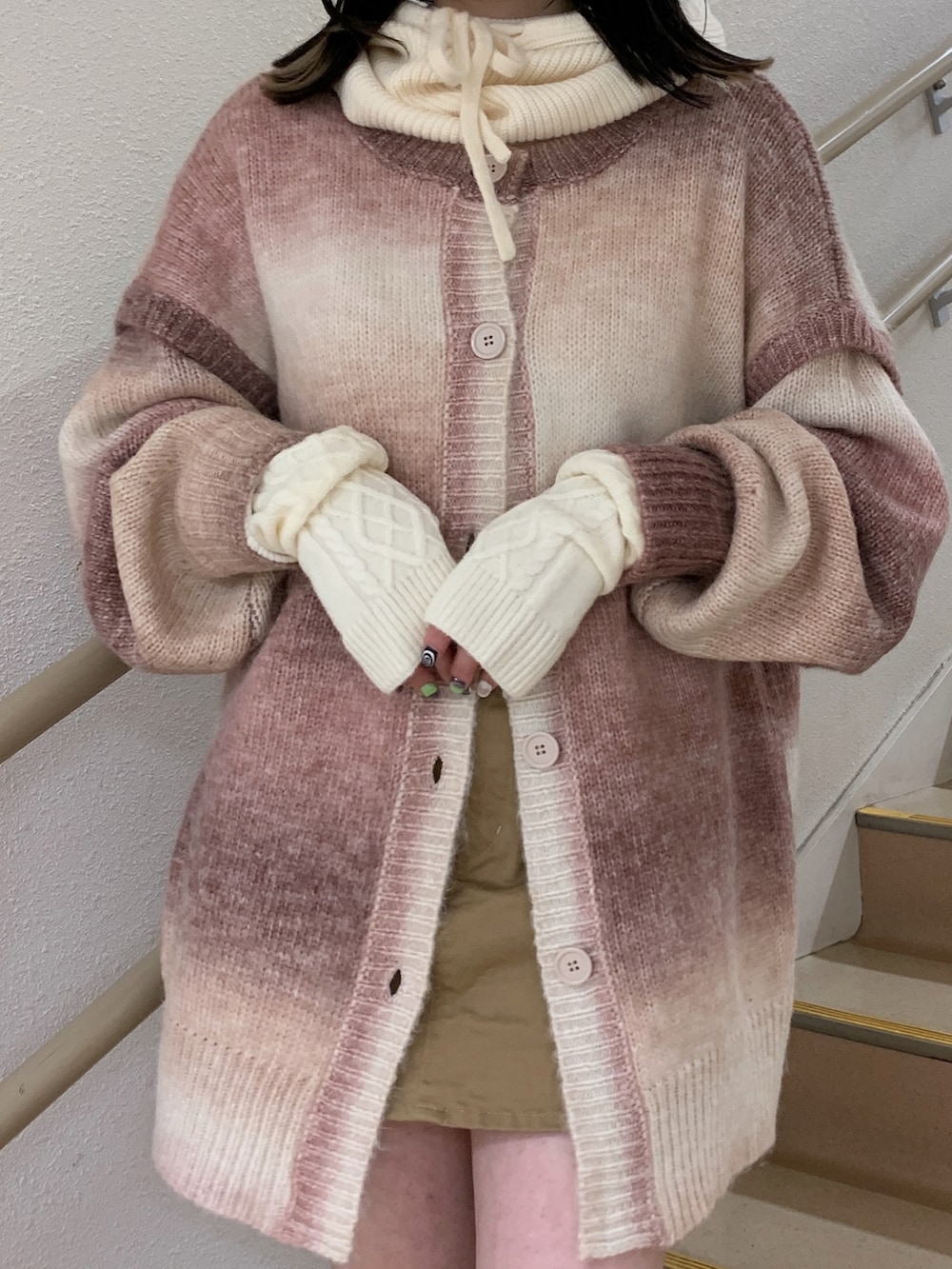 ピンク系のカーディガン/ボレロ、ベージュ系のスカート、ブラック系のブーツを着用したレディースの秋コーディネートの2枚目の写真