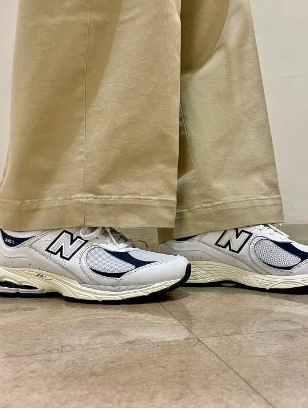 ブラック系のベスト、ホワイト系のパーカー、ベージュ系のチノパンツを着用したメンズの秋コーディネートの4枚目の写真