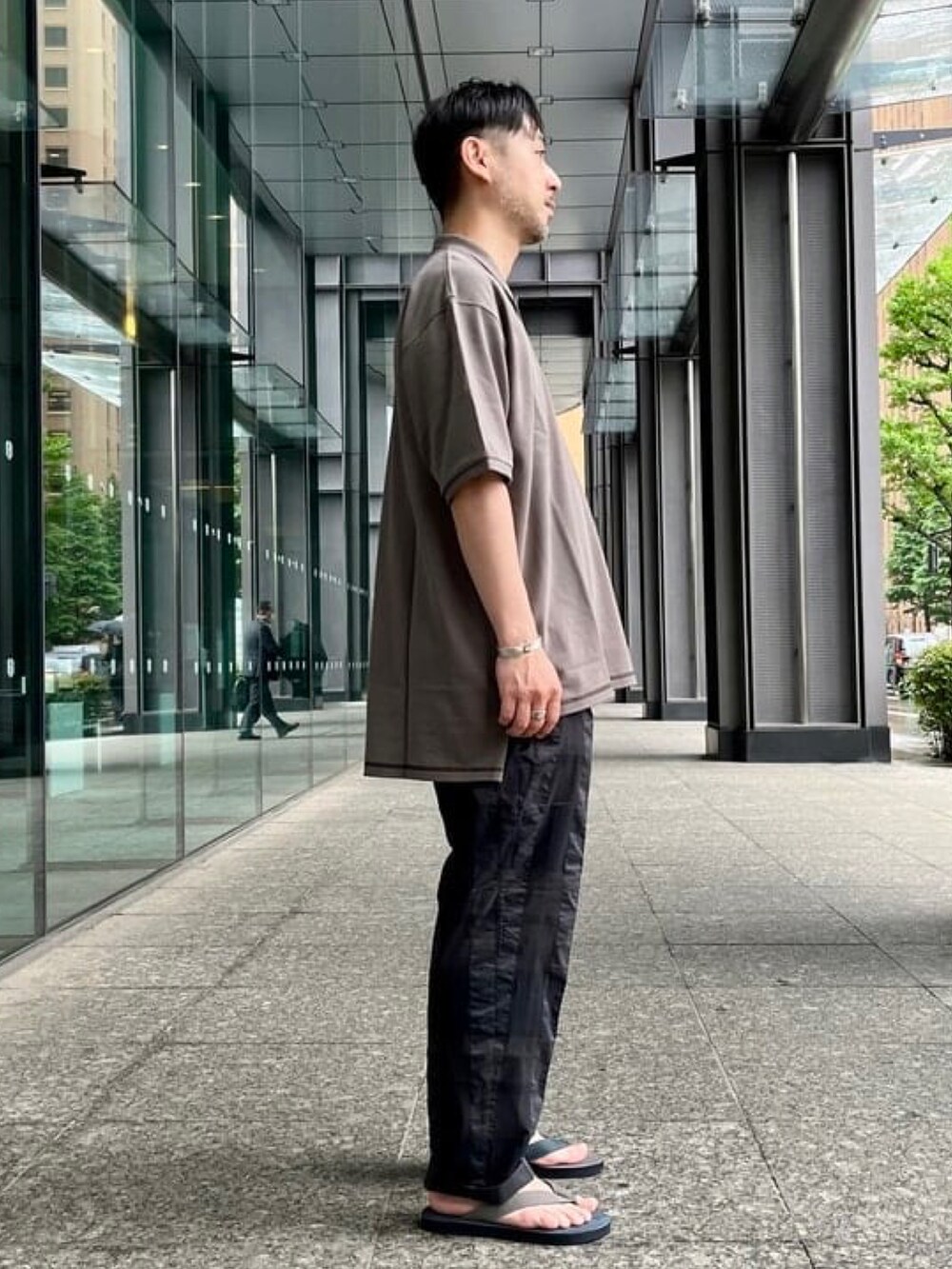 グレー系のポロシャツ、グレー系のその他パンツ、その他のサンダルを着用したメンズの春コーディネートの2枚目の写真