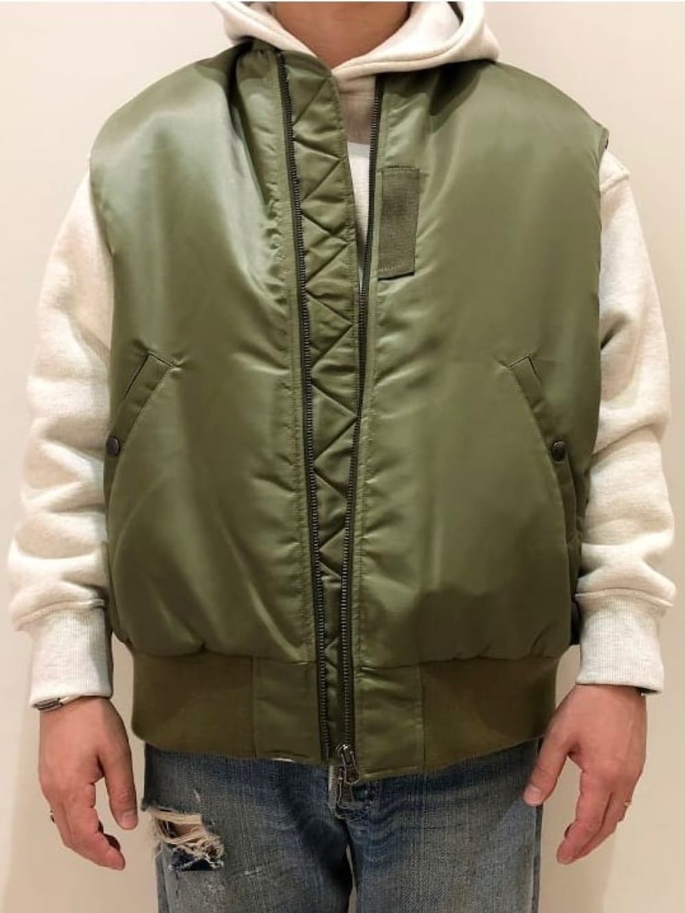 グリーン系のベスト、ホワイト系のパーカーを着用したメンズの秋コーディネートの2枚目の写真