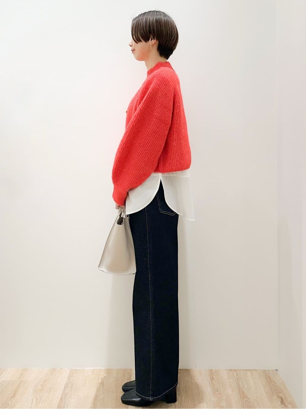 レッド系のニット/セーター、ホワイト系のTシャツ/カットソー、ブルー系のデニムパンツを着用したレディースの冬コーディネートの2枚目の写真