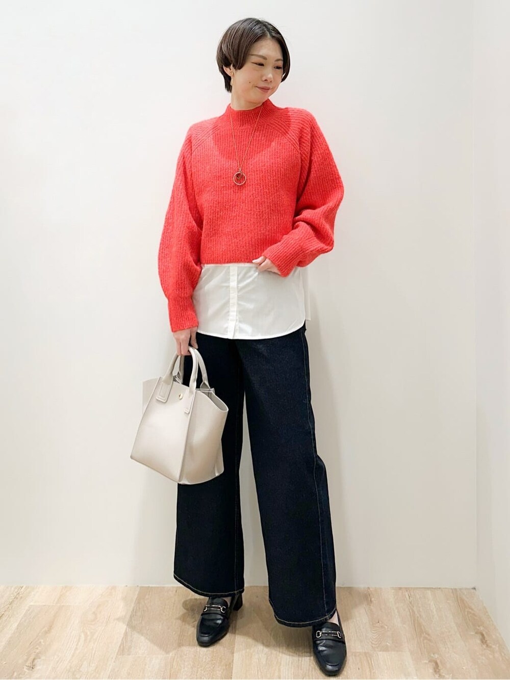 レッド系のニット/セーター、ホワイト系のTシャツ/カットソー、ブルー系のデニムパンツを着用したレディースの冬コーディネートの4枚目の写真
