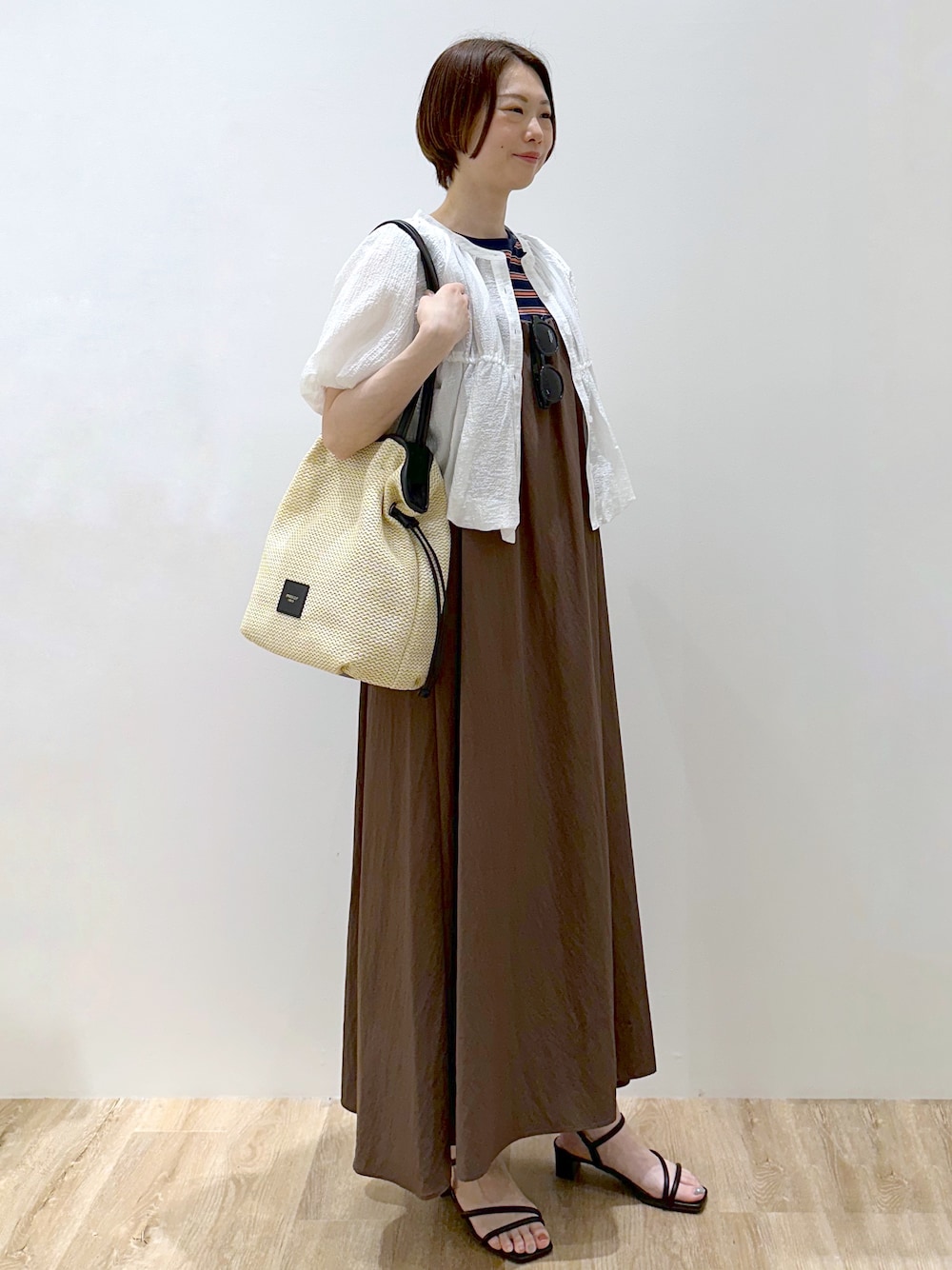 ブルー系のTシャツ/カットソー、ブラウン系のワンピース、ホワイト系のトートバッグを着用したレディースの春コーディネートの2枚目の写真