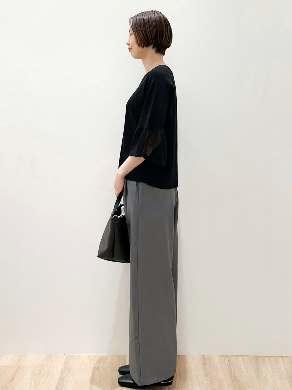 ブラック系のパンプス、グレー系のその他パンツ、ブラック系のショルダーバッグを着用したレディースの春コーディネートの2枚目の写真