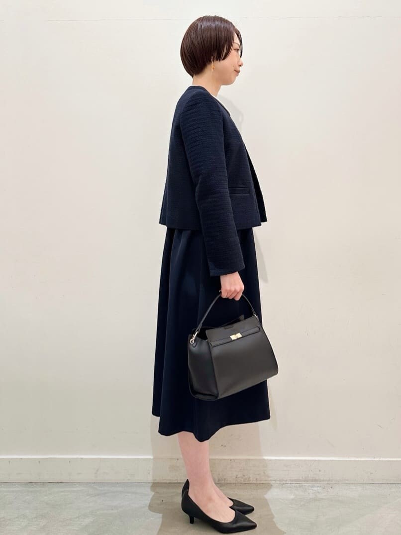 ブルー系のノーカラージャケット、ブルー系のワンピース、ブラック系のトートバッグを着用したレディースの冬コーディネートの2枚目の写真