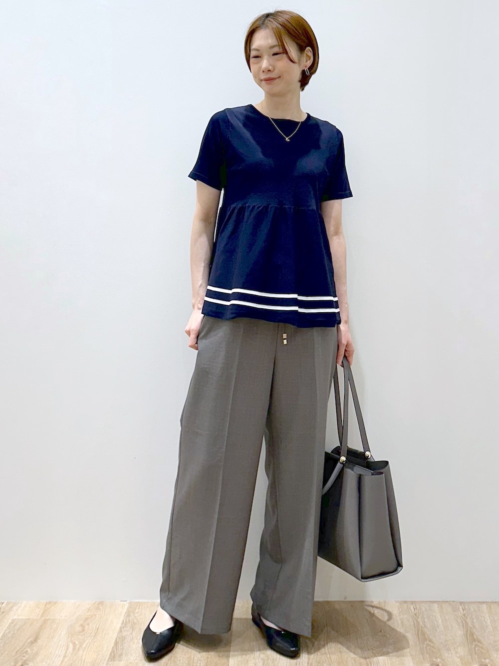 ブルー系のニット/セーター、グレー系のその他パンツ、グレー系のトートバッグを着用したレディースの夏コーディネートの2枚目の写真