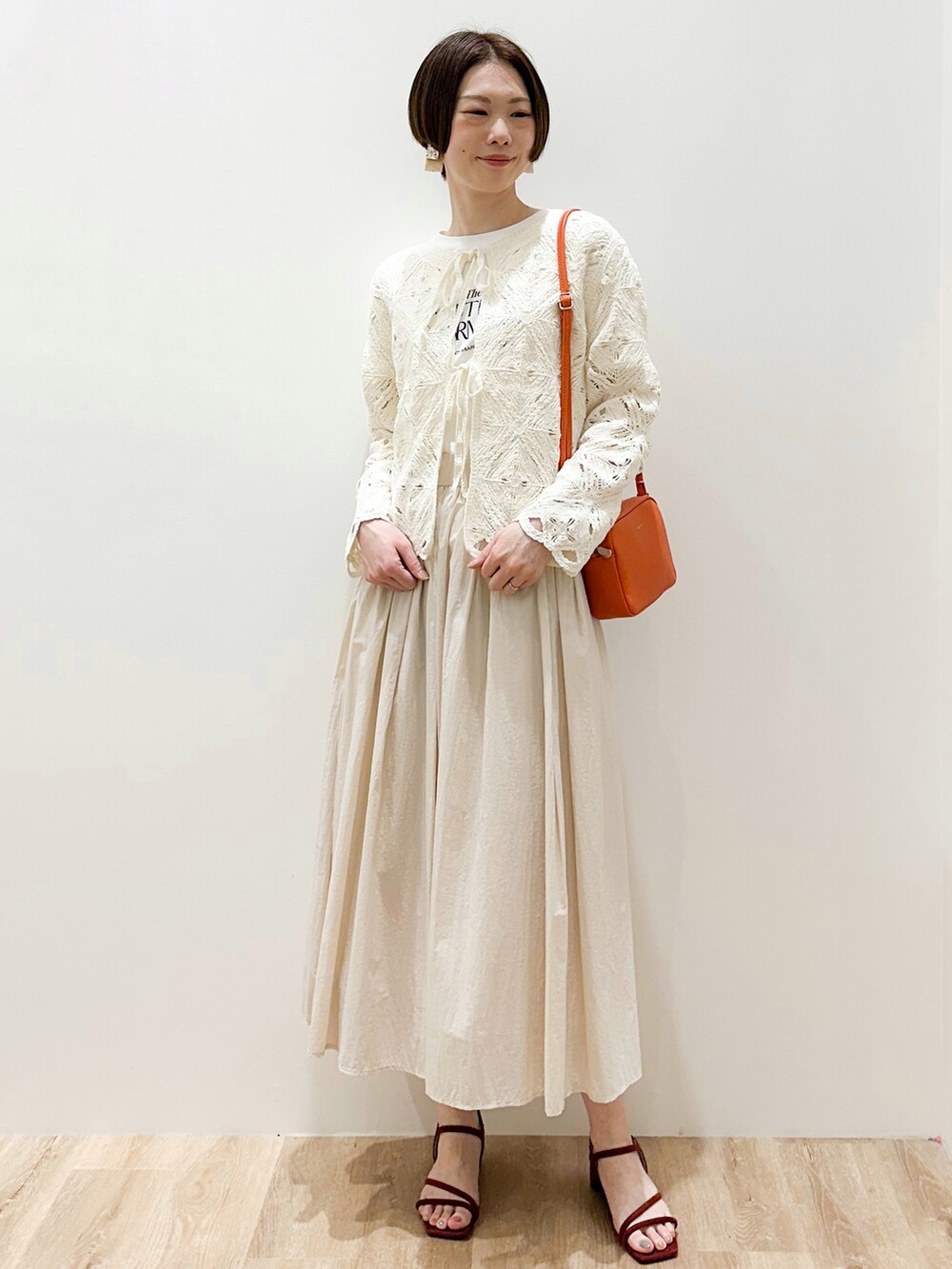 ベージュ系のスカート、レッド系のサンダル、ホワイト系のTシャツ/カットソーを着用したレディースの春コーディネートの2枚目の写真