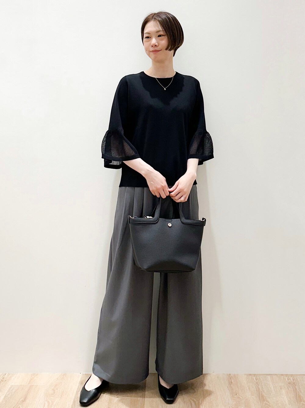 ブラック系のパンプス、グレー系のその他パンツ、ブラック系のショルダーバッグを着用したレディースの春コーディネートの4枚目の写真