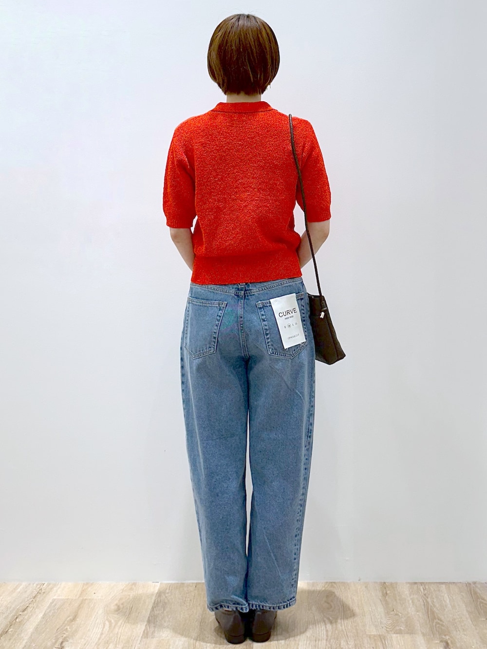 レッド系のカーディガン/ボレロ、ブルー系のデニムパンツ、ブラウン系のショルダーバッグを着用したレディースの夏コーディネートの5枚目の写真